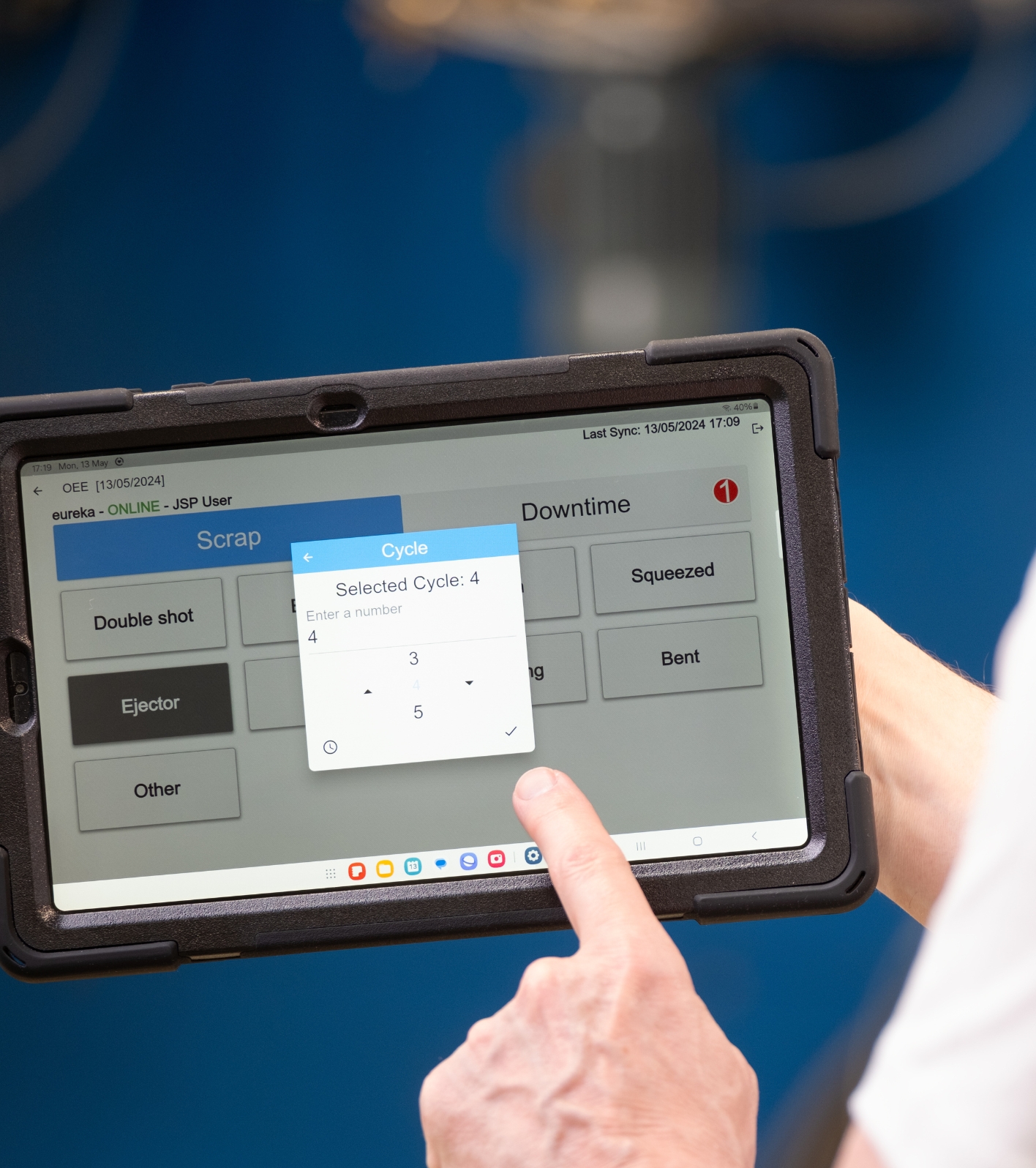 iPad s rukou zobrazující časy cyklu z vstřikovacího stroje
