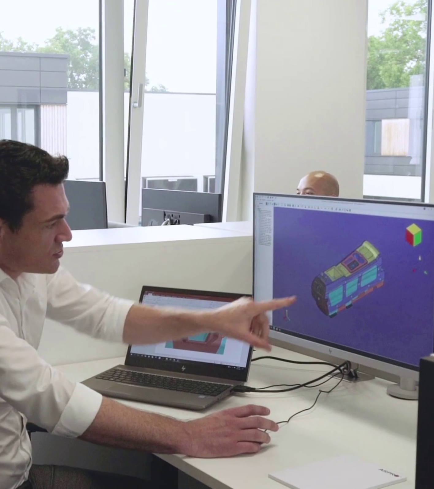 Ein JSP-Ingenieur in weißem Hemd zeigt auf ein FEA-Design auf einem Computerbildschirm