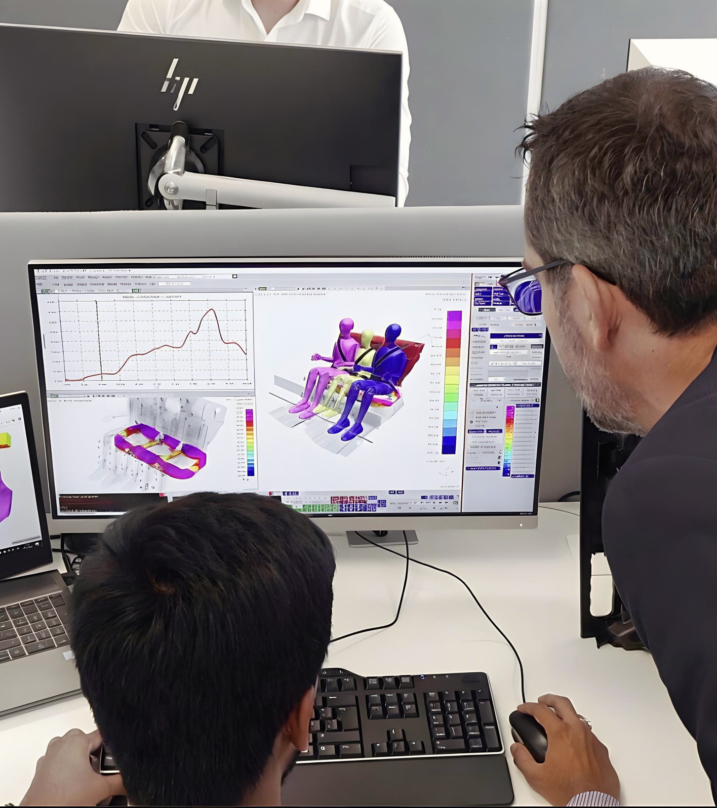 Zwei Herren betrachten CAD- und FEA-Simulationen auf Computerbildschirmen