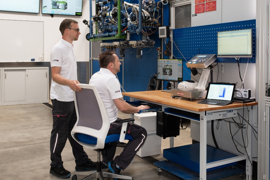 Dos hombres con polos ARPRO en el Innovation Centre observando un ordenador en producción.