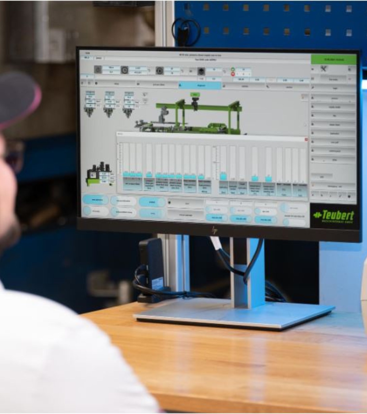 Hombre mirando pantalla con estadísticas de planta de moldeo telemétrica.