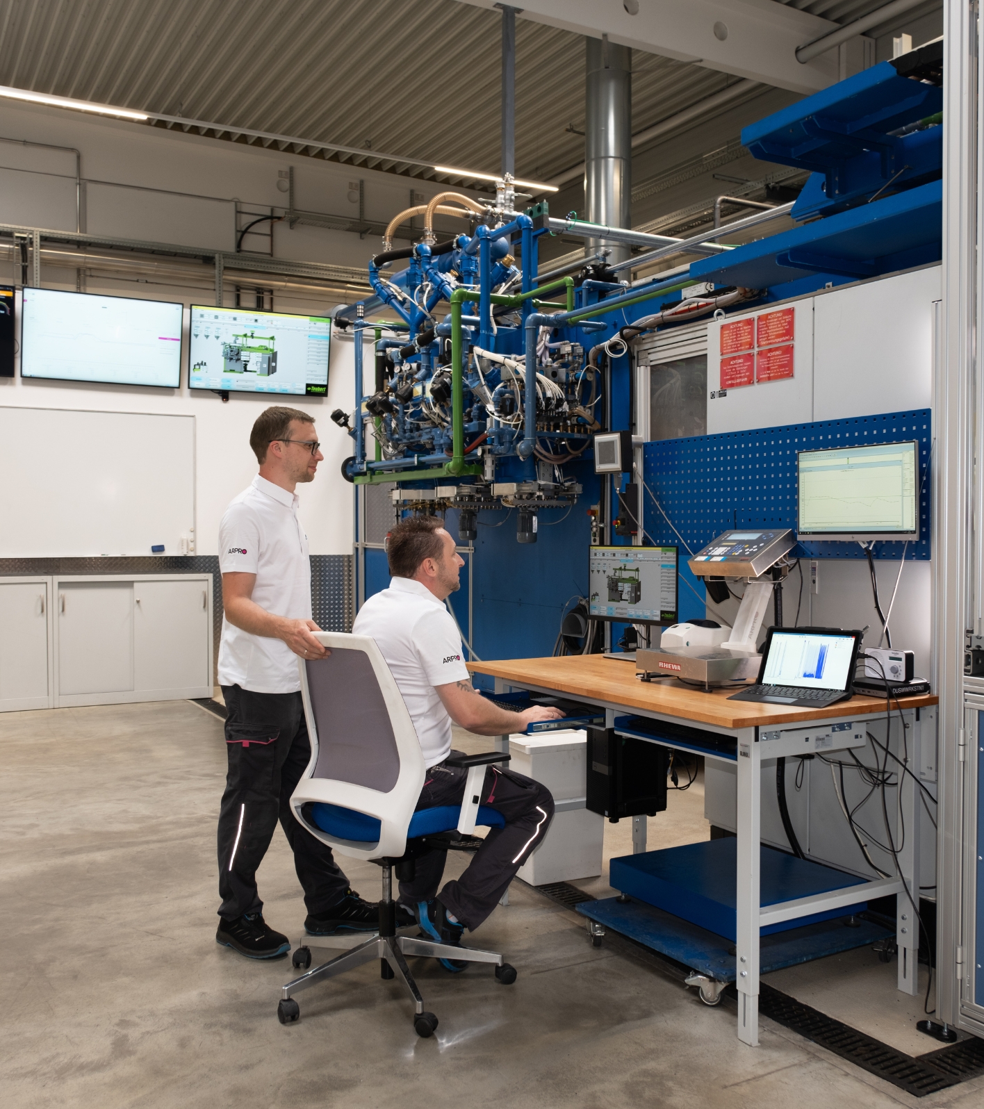 JSP Production Support, two gentlmen sitting at a computer next to a moulding machine