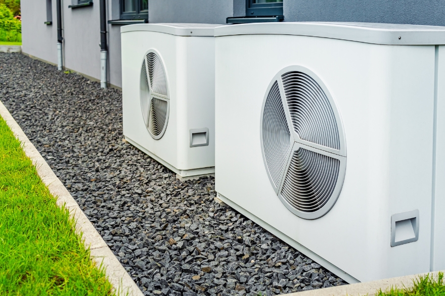 White heat pumps sitting on grey stones