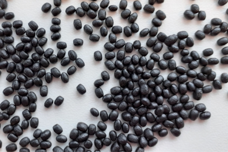 Close-up of black expanded foam beads randomly scattered across a white surface.