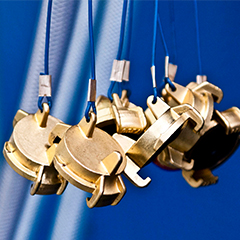 Gold coloured caps for pipes on a moulding press, on a blue background with light blue pipes.